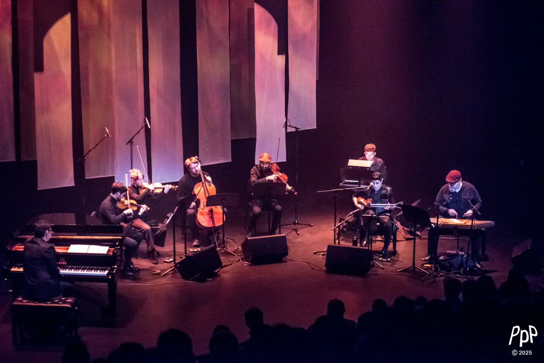 L’ensemble au complet sur scène — piano, quatuor à cordes, synthétiseur, târ et santur — sous de hauts panneaux suspendus baignés d’une lumière chaude.